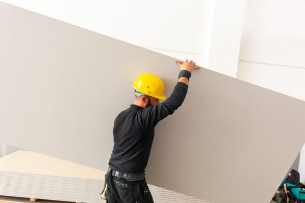 Worker at work in the construction of a plasterboard wall.